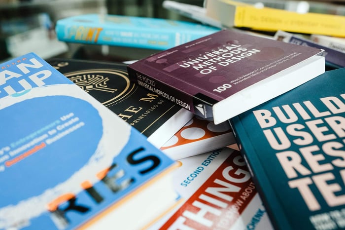 A collection of various design books piled on a table, showcasing diverse titles and covers.