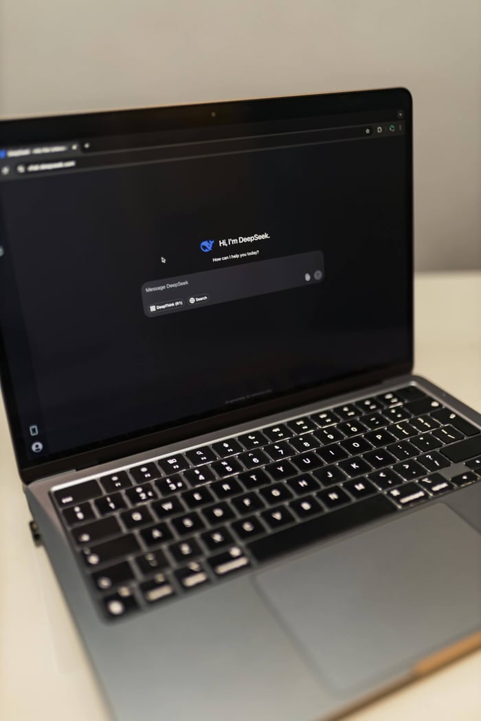 Close-up of a laptop showing an AI chat interface in a dimly lit room.