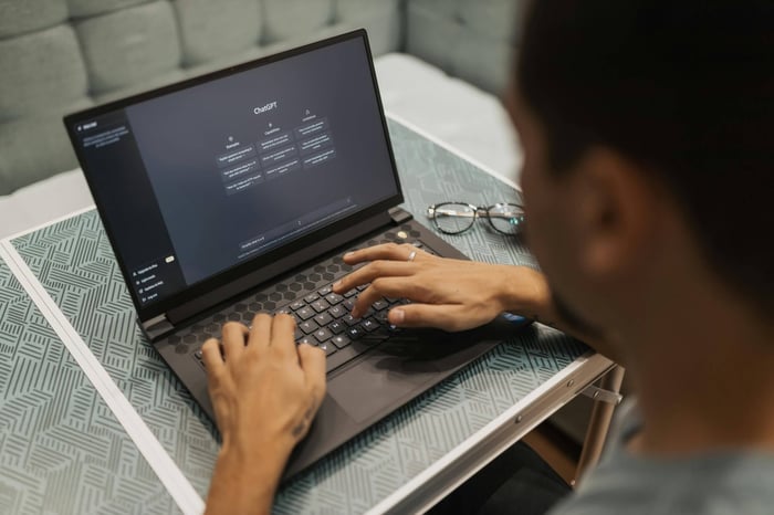 A person using a laptop to interact with AI technology indoors during the day.